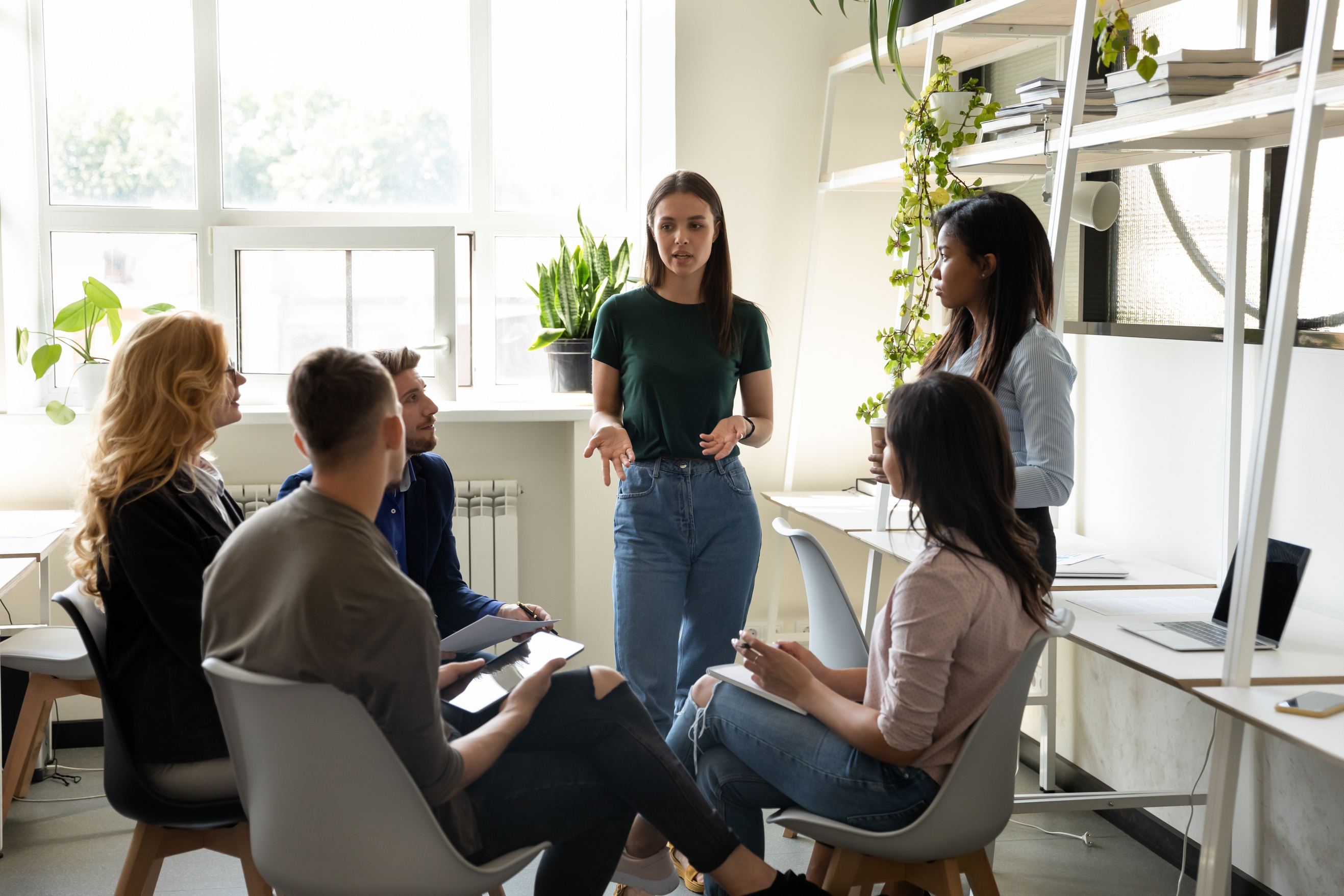 Diverse office workers listens team leader at group meeting